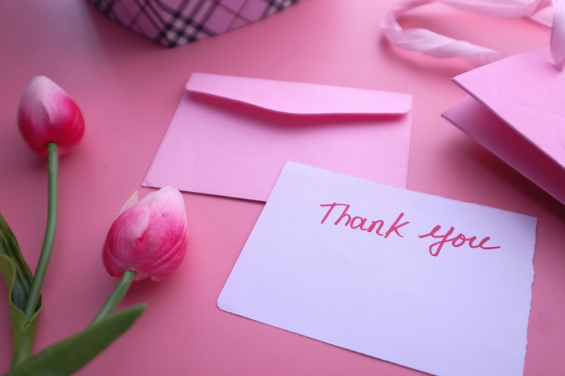 A Thank You Letter Near Pink Flowers and Envelope