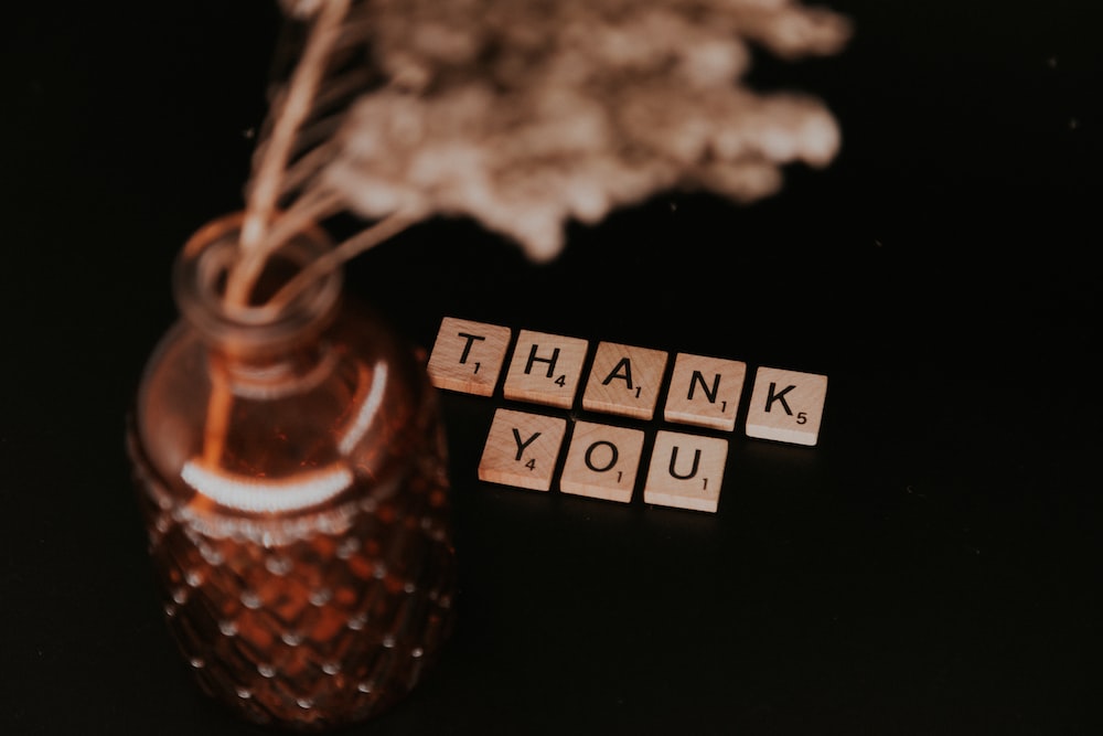 Clear glass bottle with white flowers and Thank You pieces